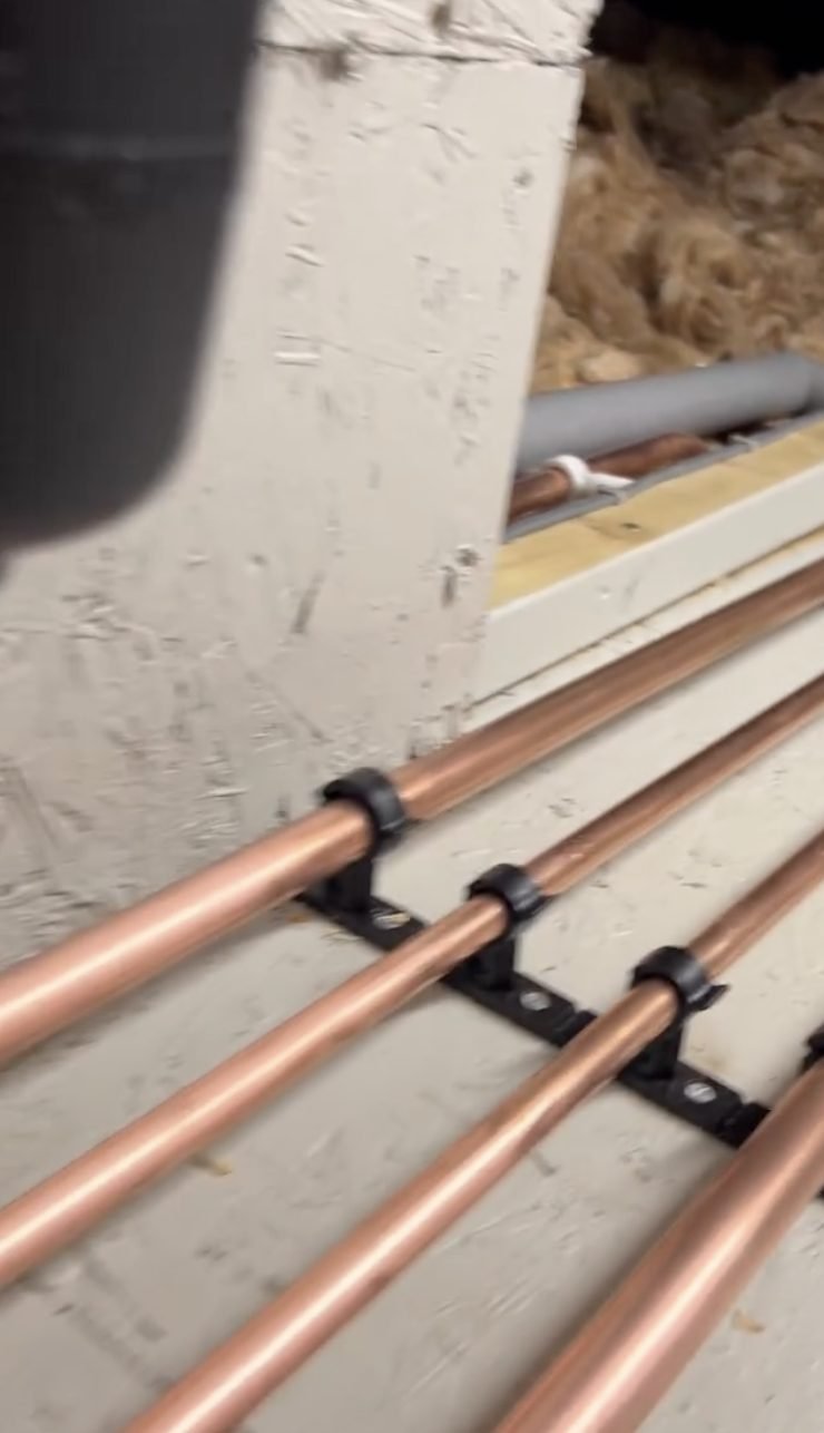 Copper heating pipes clipped neatly along a wall