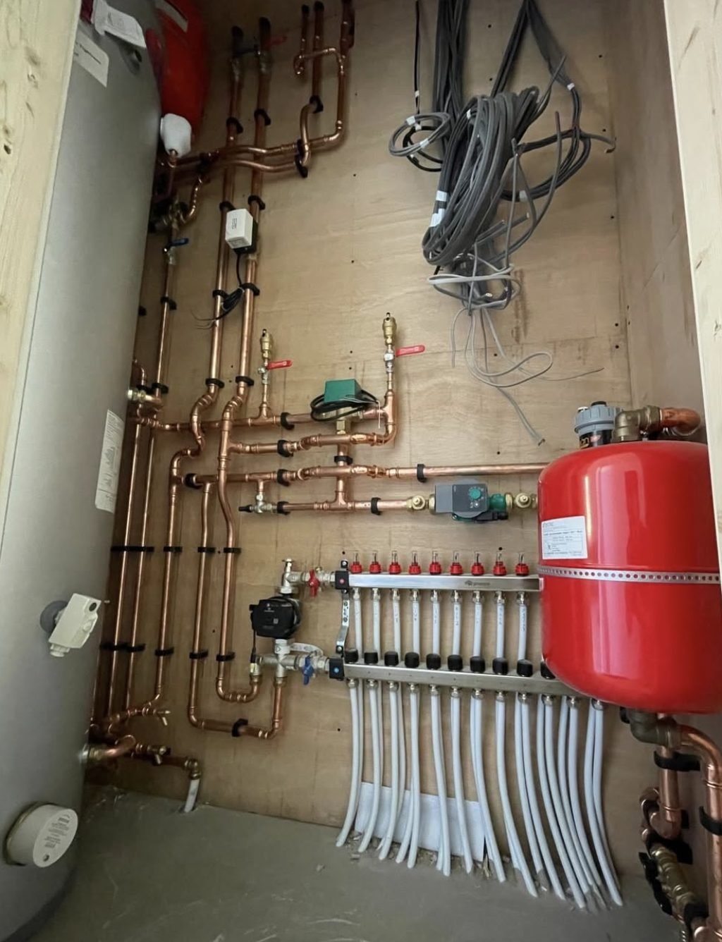 Underfloor heating manifold with expansion vessel, pumps and copper pipework in a plant room